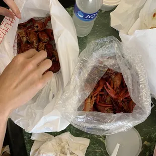 a person grabbing a sandwich from a plastic bag