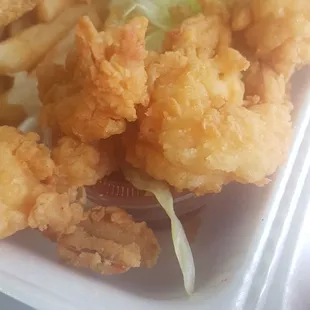 fried shrimp and fries in a styrofoam container