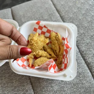 a hand picking up some fried chicken