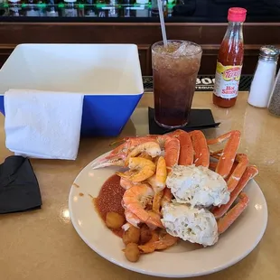 a plate of crab legs, potatoes, and coleslaw