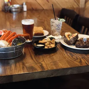 A meal for two: crab legs, gator bites, and a tender steak with a baked potato