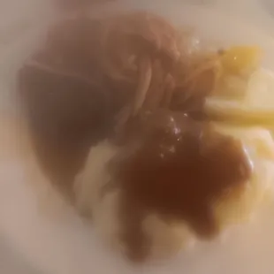 Close up of mashed potatoes and gravy with hamburger steaks and spaghetti etc