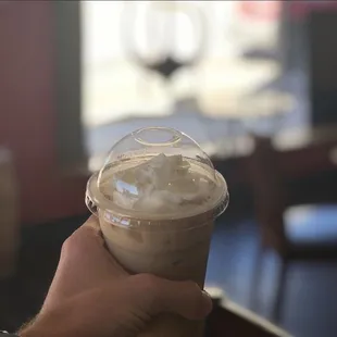 a hand holding a cup of iced coffee