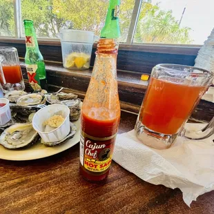 a plate of oysters and a bottle of sauce