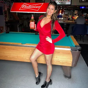 a woman in a red dress posing in front of a pool table