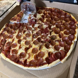 a person cutting a pepperoni pizza