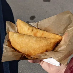 Two empanadas, hand shown for scale.