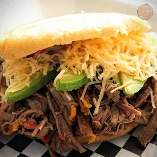 Arepa stuffed with shredded beef, shredded gouda and avocado. It&apos;s a Venezuelan typical dish.