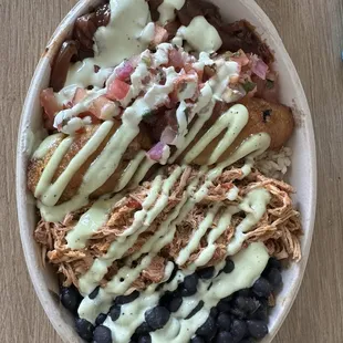 Create Build Your Own Bowl Beans, shredded chicken, sweet plantains, brown rice, pico de gallo, caramelized onions, cilantro sauce.