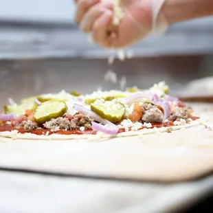 a hand sprinkling cheese on a pizza