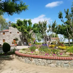 a circular flower bed in front of a stone building