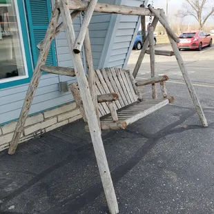 a wooden swing in front of a building