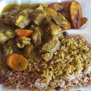 Curry goat served with rice and peas and a side of plantains