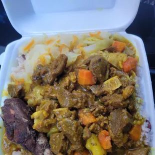 The number five curry goat with rice and beans and an extra piece of jerk chicken