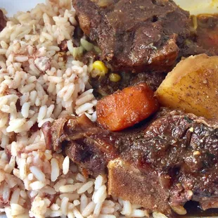 Oxtails, rice and peas, and stewed cabbage buried underneath the oxtails.