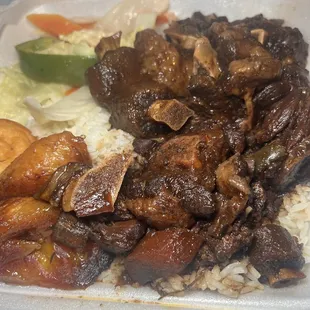 Oxtail with white rice, steamed vegetables, plantains and sweet bread.