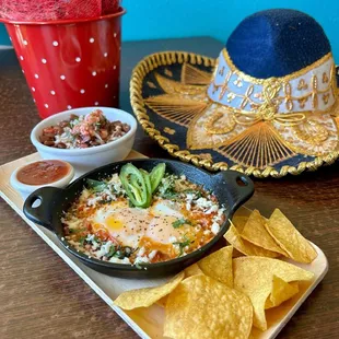 Huevos Ahogados $16
2 sunny side up eggs on a ranchera sauce skillet, with whole pinto beans and tortillas.