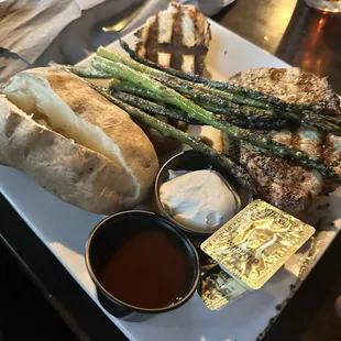 Grilled pork chops with asparagus, baked potato and grilled bread.