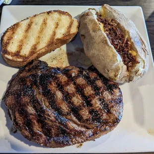 Gorgeous, table side-cut ribeye, served with a massive baked potato and buttery, grilled bread.