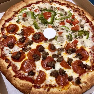 Large pizza with pepperoni and sausage on one side and veggies on the other.