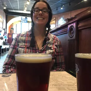 a woman sitting at a table with two beers
