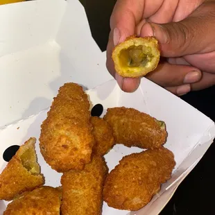 a person holding a piece of fried food
