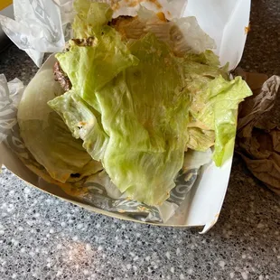 Lettuce. One slice of tomato. Slice of yellow cheese. One patty. Onion.