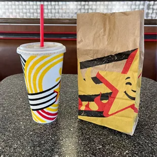 a drink and a paper bag on a table