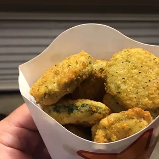 a hand holding a basket of fried food