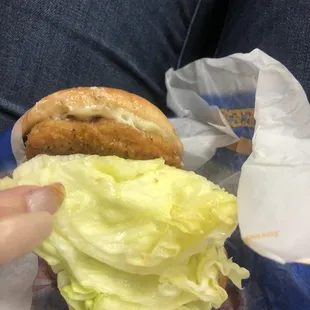 a person holding a sandwich with lettuce