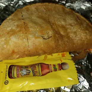 a sandwich wrapped in foil with a bottle of ketchup