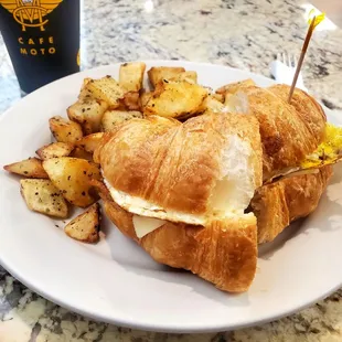 a croissant sandwich and potatoes