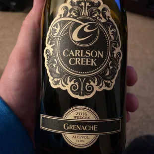 a hand holding a bottle of wine