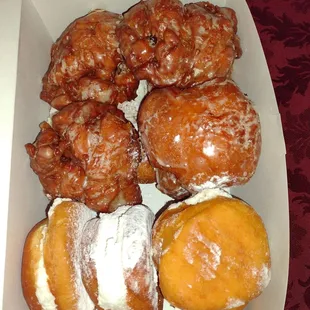 A dozen doughnuts with marshmallow, apple fritter, and their famous potato doughnut on top.