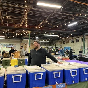 a man standing in front of a table of coolers