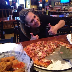 a woman sitting in front of a pizza