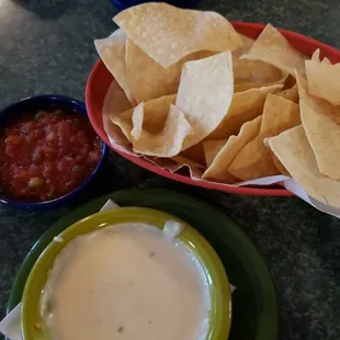 a plate of tortilla, chips, salsa, and a bowl of guacamole