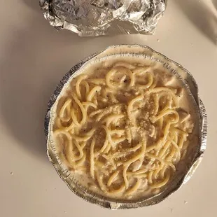 Spaghetti and chicken in white sauce. This meal came with fresh garlic bread and is pictured in a To Go dish.