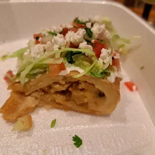Inside half a chicken empanada topped with fresh lettuce, sour cream, guacamole, pico de gallo, queso fresco, and salsa verde