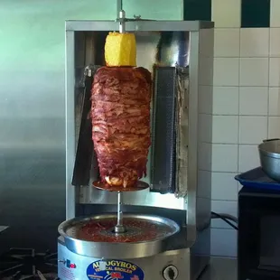 Meat on a stick slowy roasting with a pineapple on top