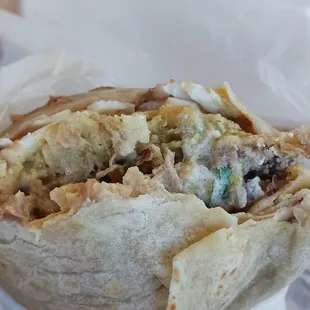 Chilaquiles burrito with beans, carnitas, and over easy eggs.