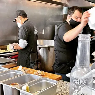 two men preparing food in a kitchen