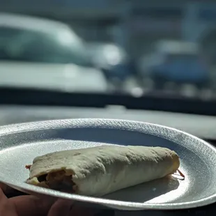 a person holding a plate with a burrito on it