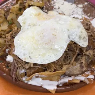Chilaquiles con carnitas, huevos, frijoles y guisado de papas