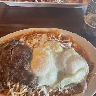 Gigantic plate of chilaquiles rojos with 2 eggs and carne asada