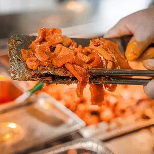a person holding a piece of meat with chopsticks