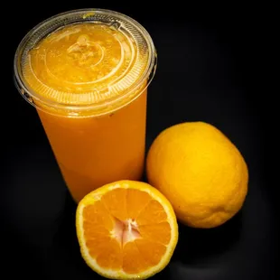 a glass of orange juice next to an orange