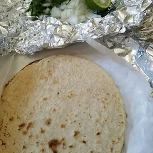Corn tortillas (3), onions, cilantro, and limes come with the plates.