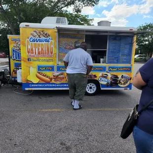 a man and a woman standing in front of a food truck