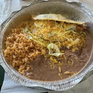 One shredded  beef taco with lettuce, rice and beans.